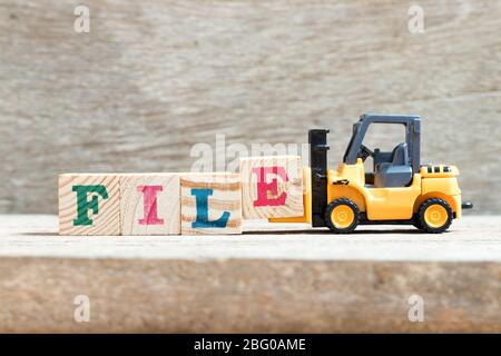 Toy forklift hold letter block e in word file on wood background Stock Photo