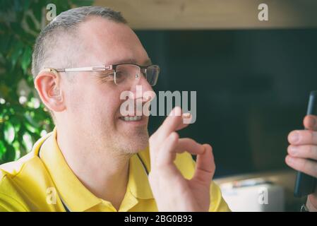Smiling Deaf man talking using sign language on the smart phone's cam Stock Photo