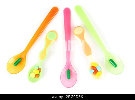 Plastic spoons with color pills, isolated on white Stock Photo