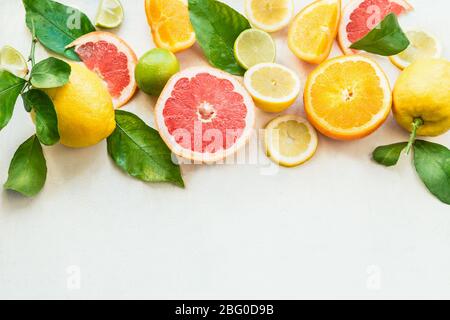 Various citrus fruits border with green leaves on white background. Top view. Halves of citrus. Vitamin C. Healthy natural immune boosters Stock Photo