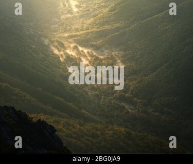 Very first rays of light on an autumn day over grasslands and forests in Ancares Mountain range Stock Photo