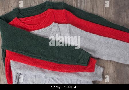 Clothing, fashion, style. Multicolored sweaters are placed on a wooden table. The clothes are neatly folded. Hygge, cozy, cashmere, soft. Home routine Stock Photo