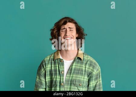 Curly young guy whining from despair or stress on color background Stock Photo