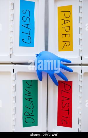 Above view background of four plastic bins labeled for storage and sorting waste at home, with blown rubber glove on top, copy space Stock Photo