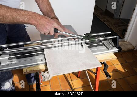the mason cuts a ceramic tile with a tile cutter Stock Photo