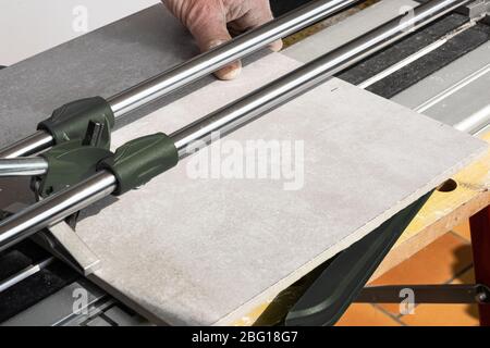the mason cuts a ceramic tile with a tile cutter Stock Photo