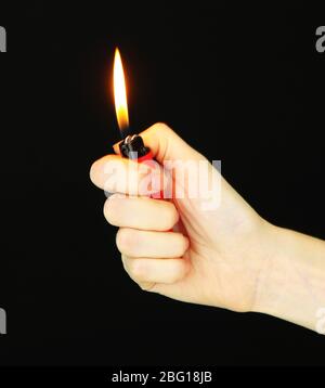 Burning lighter in female hand, isolated on black Stock Photo