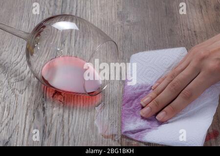 A woman wipes a wine stain with a paper napkin. The hand removes the spilled glass of wine. The woman does the cleaning. Clean, house, housekeeper, cl Stock Photo