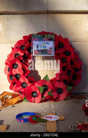 A red poppy wreath laid in front of a war memorial on remembrance day
