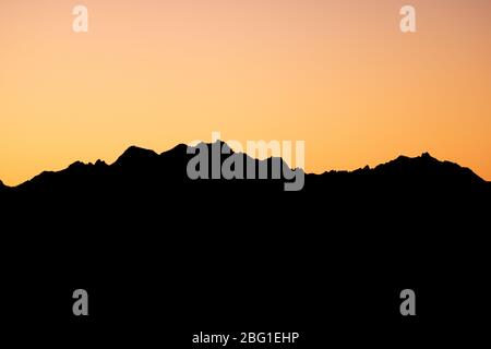 Orange Sun Setting Behind the Mountains Stock Photo