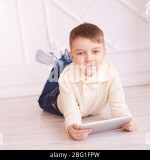 Cute boy. Computer tablet. Training. light interior Stock Photo