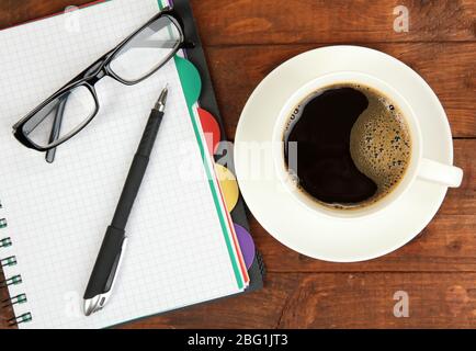 Cup of coffee on worktable covered with documents close up Stock Photo