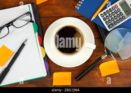 Cup of coffee on worktable covered with documents close up Stock Photo