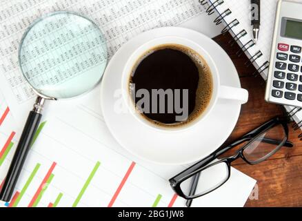 Cup of coffee on worktable covered with documents close up Stock Photo
