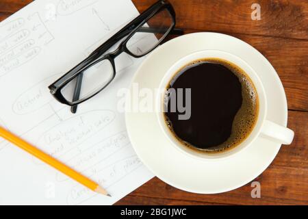 Cup of coffee on worktable covered with documents close up Stock Photo