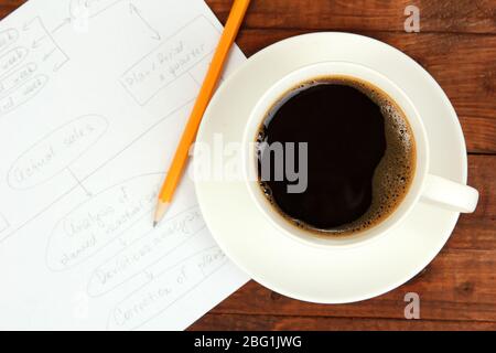 Cup of coffee on worktable covered with documents close up Stock Photo