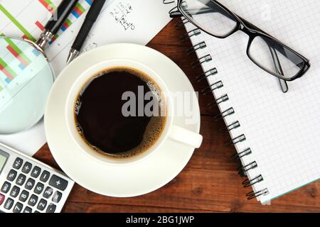 Cup of coffee on worktable covered with documents close up Stock Photo