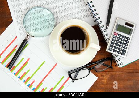 Cup of coffee on worktable covered with documents close up Stock Photo