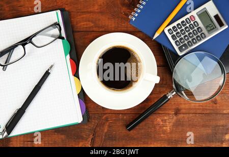 Cup of coffee on worktable covered with documents close up Stock Photo
