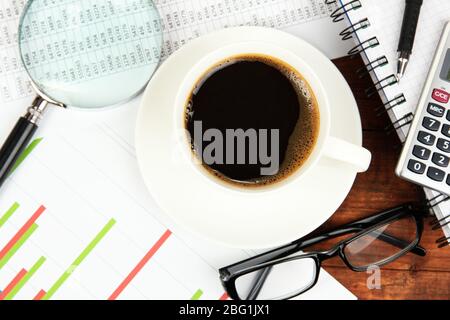 Cup of coffee on worktable covered with documents close up Stock Photo