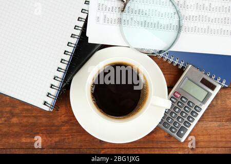Cup of coffee on worktable covered with documents close up Stock Photo
