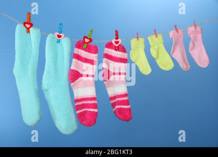 Colorful socks hanging on clothesline, on color background Stock Photo