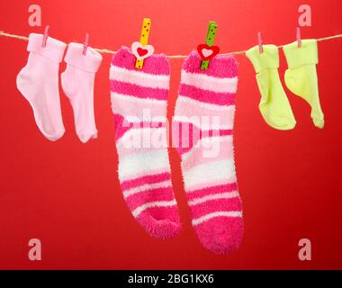 Colorful socks hanging on clothesline, on color background Stock Photo