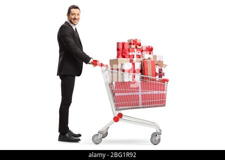 Full length profile shot of a businessman with a pile of presents in a shopping cart isolated on white background Stock Photo