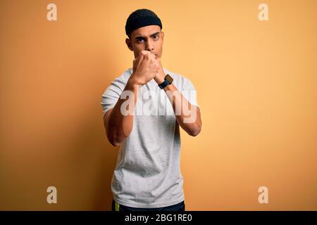 Handsome african american sportsman doing sport wearing sportswear over yellow background Ready to fight with fist defense gesture, angry and upset fa Stock Photo