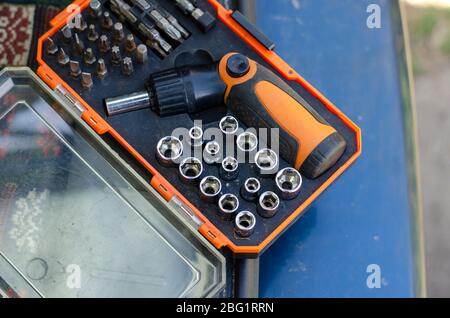 Screwdriver with a set of bits. Used bit set for screwdriver in plastic box. Hand tools in the household. View from above. Selective focus. Stock Photo