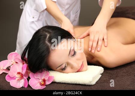 Beautiful young woman in spa salon getting massage with spa stones, on dark background Stock Photo