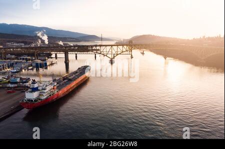 Aerial drone shot of a industrial shipyard and cargo ship loading port with cargo ships in Vancouver, BC, Canada. Stock Photo