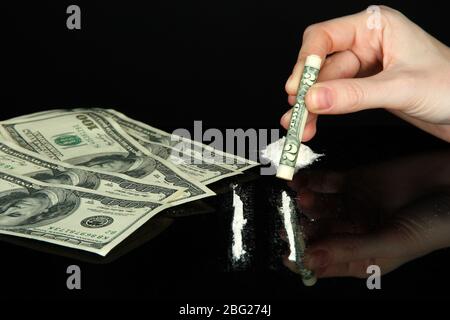 Cocaine drugs lines and female hand holding rolled dollar banknote, close up Stock Photo