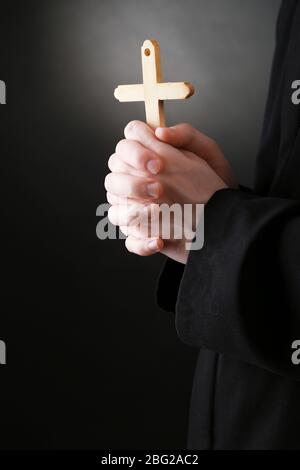 Priest holding cross, on black background Stock Photo