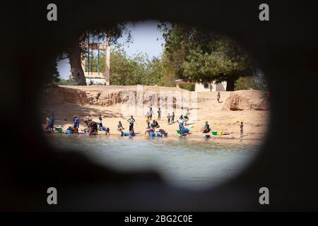 Villagers washing their clothes on the banks of the Senegal River viewed from aboard the Bou el Mogdad antique river boat. Stock Photo