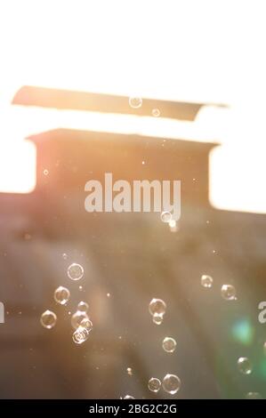Soap bubbles in blurry view on sunlit orange chimney at home Stock Photo