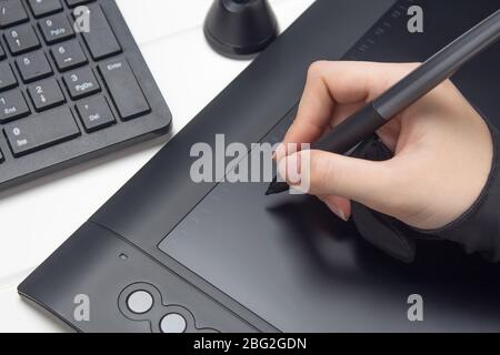 Graphic designer working on digital tablet. The hand draws on a graphics tablet. Freelance, designer, Illustrator. Technology, remote work, outsourcin Stock Photo