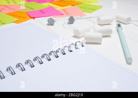 Daily planner, pen, headphones, and colorful word cards. Close-up on a white background. Copy space. Clean sheet. To-do list, marshmallow. Color sheet Stock Photo