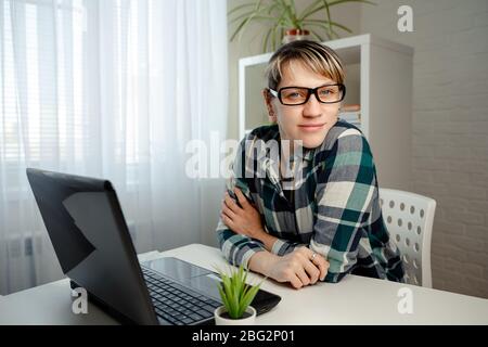 Young woman works remotely from home at the computer. Stay home safe Stock Photo