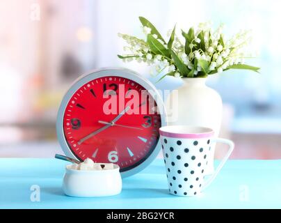 Cup tea and clock on bright background Stock Photo