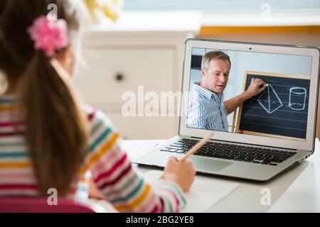 Middle-aged distance teacher having video conference call with pupil using webcam. Online education and e-learning concept. Home quarantine distance Stock Photo