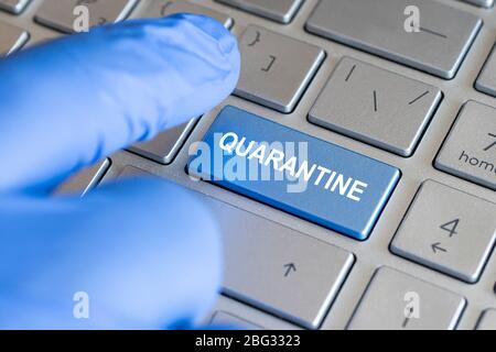 Closed up finger in a blue glove on keyboard with word QUARANTINE Stock Photo