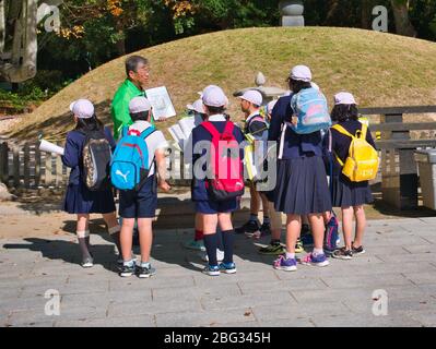 A group of school children with a teacher on a trip to the Hiroshima Peace Park to learn about the history of the atomic bombs at the end of World War Stock Photo