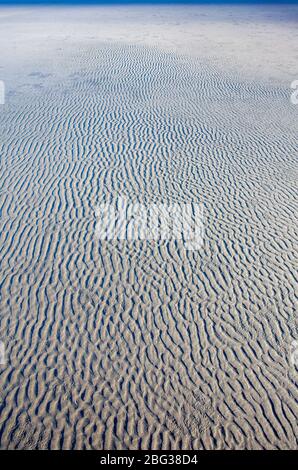 The natural movement of waves and wind formed patterns in the flat beach sand on the Washington State coast. Stock Photo