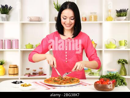 Beautiful girl wants to eat delicious pizza on kitchen background Stock Photo