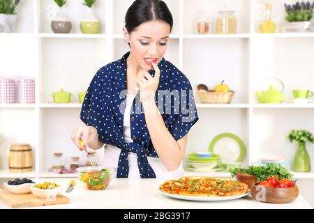 Pretty girl selects pizza or diet on kitchen background Stock Photo