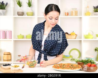 Pretty girl selects pizza or diet on kitchen background Stock Photo