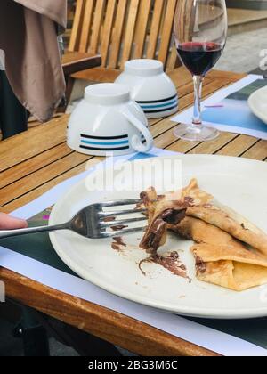 Person eating a chocolate pancake with red wine, France Stock Photo