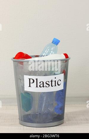 Assorted trash in bucket on room background Stock Photo