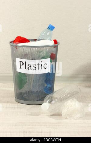 Assorted trash in bucket on room background Stock Photo